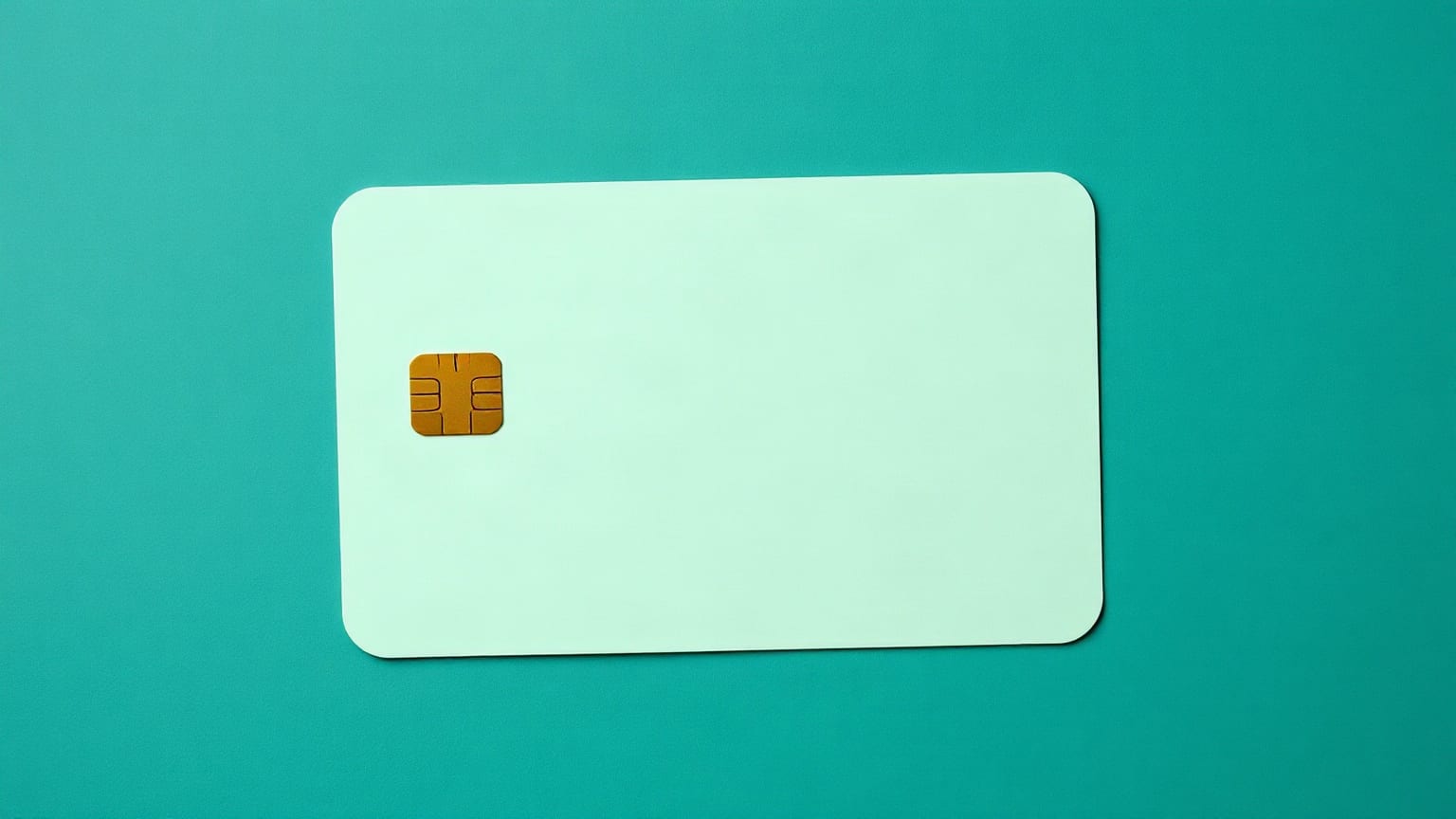 A blank pale mint payment card with a small gold chip, lying flat on deep teal